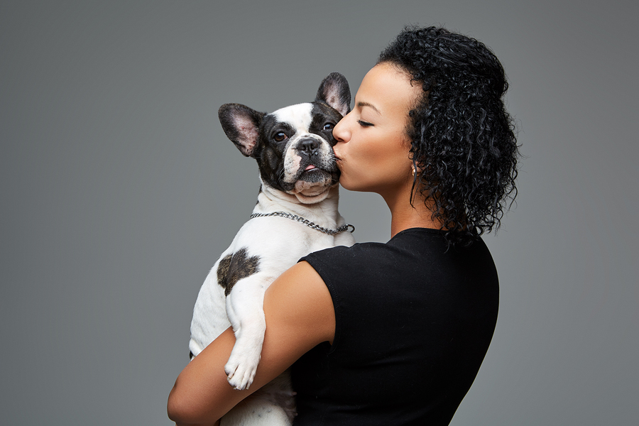An african lady kissign a french bulldog
